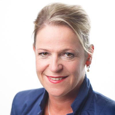 Lachende vrouw met kort blond haar in een donkerblauwe blazer